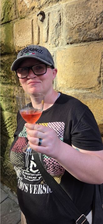 Shiloh holding a glass of rosé from a wine window